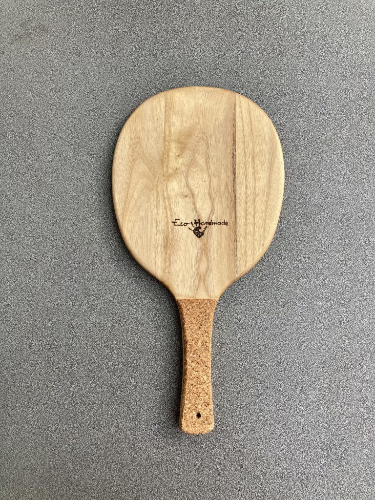 Single Frescobol wooden paddle highlighting its lightweight paulownia construction, cork grip, and minimalist engraved design