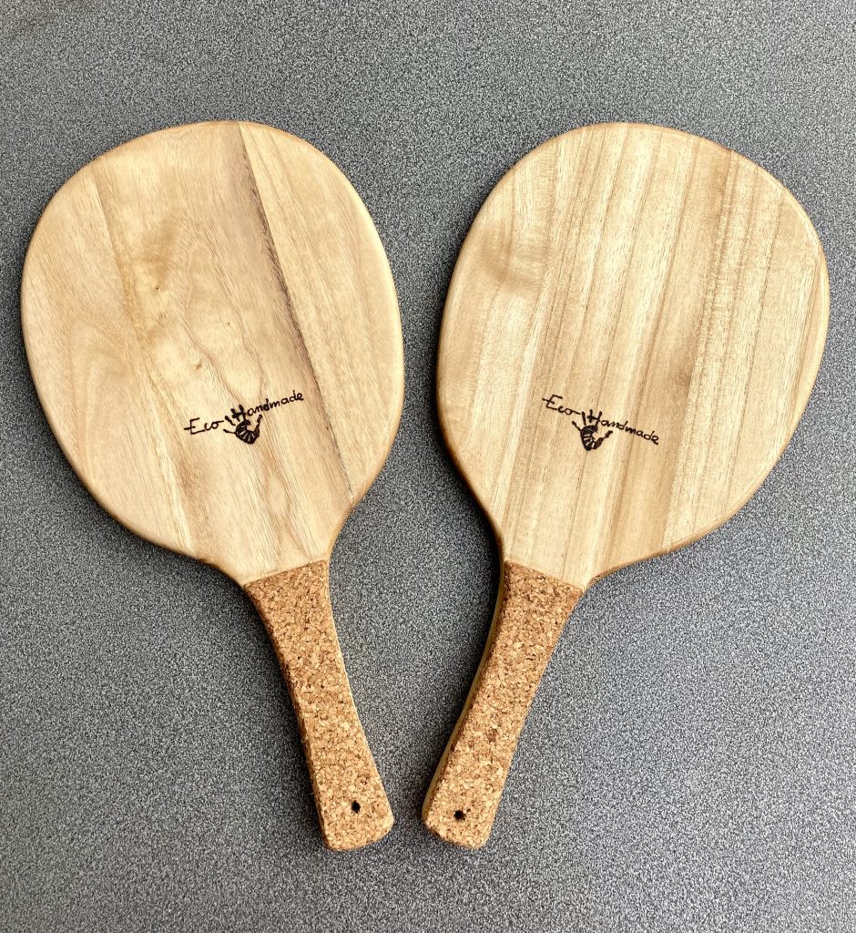 Pair of eco-friendly Frescobol wooden paddles made from paulownia wood with ergonomic cork handles, shown side by side for comparison