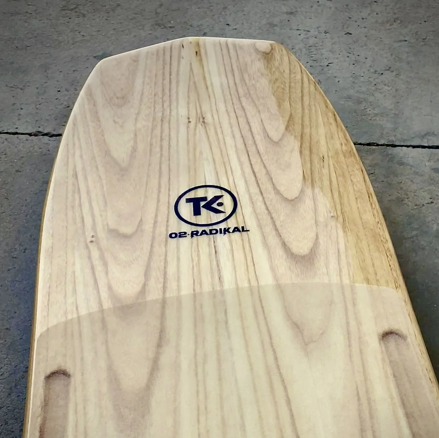 Nose of TK·02 Radikal kiteboard showing wood grain and engraved logo