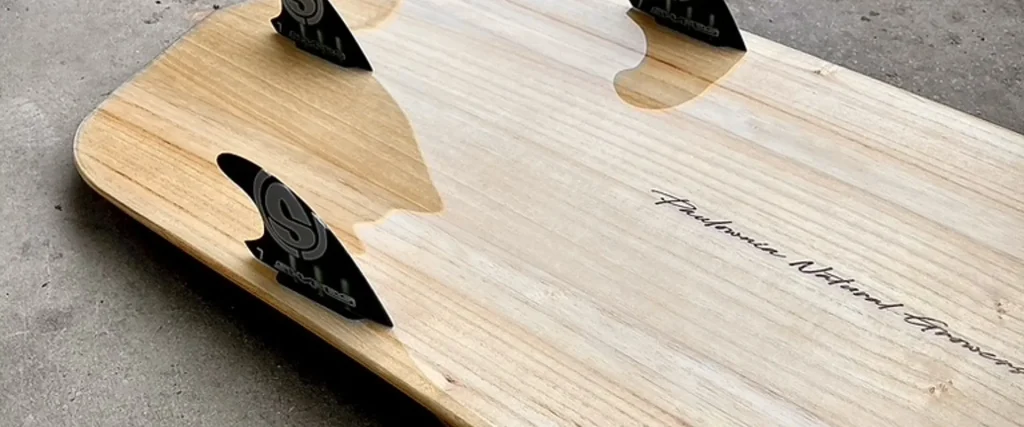 Bottom view of TK kiteboard with thruster fin setup and wood finish
