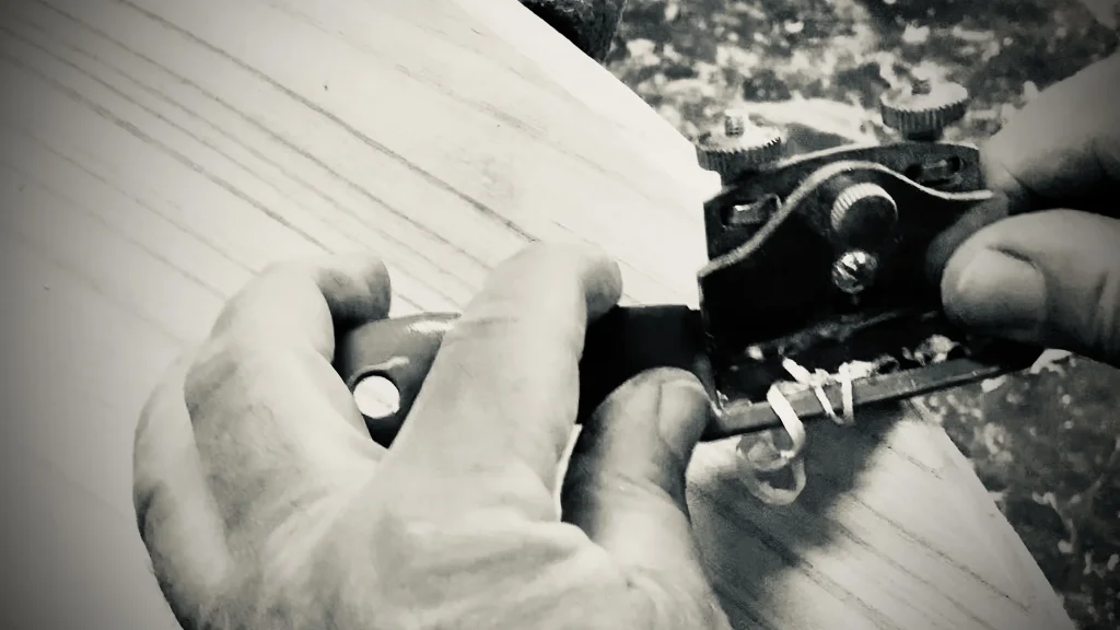 Close-up of handplaning paulownia wood while shaping a kiteboard rail. TK kiteboards