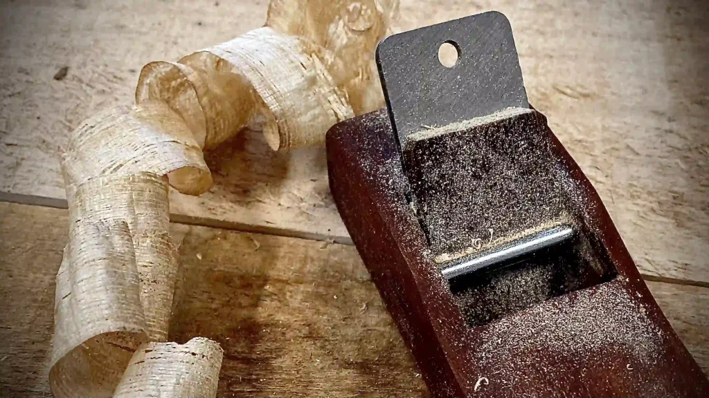 Close-up of shaping tool and curled paulownia wood shaving during board making. TK kiteboards