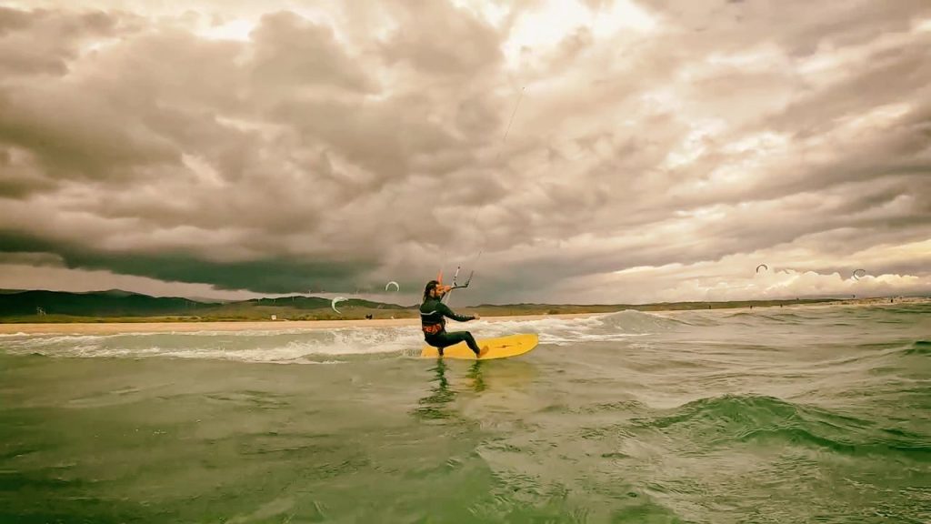 Kitesurfer riding a TK wooden board in choppy waves under stormy skies